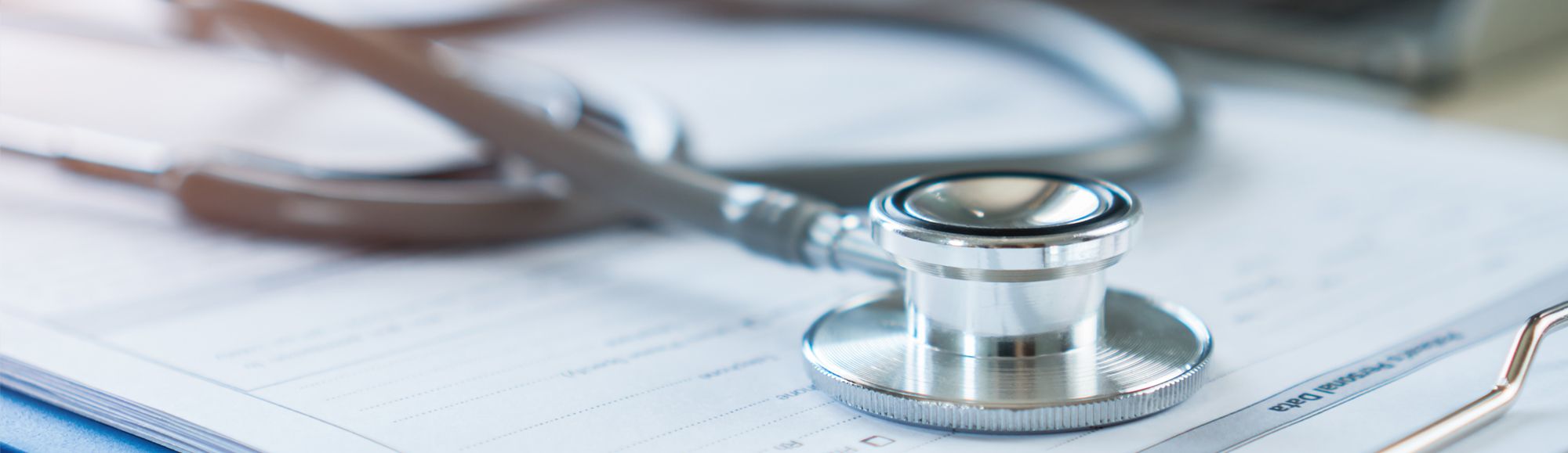 A close-up of a stethoscope resting on a stack of medical paperwork, highlighting the tools commonly used in healthcare settings for patient assessment and monitoring. The image conveys themes of medicine and health.