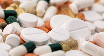 Eine Ansammlung von verschiedenen Medikamenten und Nahrungsergänzungsmitteln in Tablettenform. Die Gruppe beinhaltet weiße, orange und gelbe Kapseln sowie runde Tabletten, die unterschiedliche Größen und Farben aufweisen.